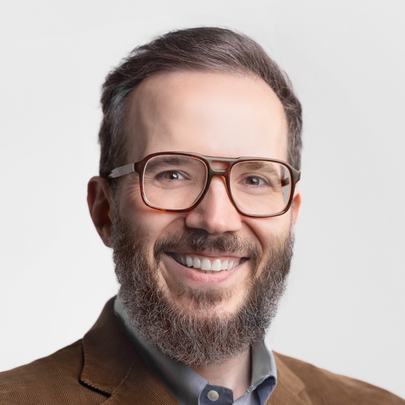 David Moldawer, smiling, in tortoiseshell glasses and a brown corduroy jacket